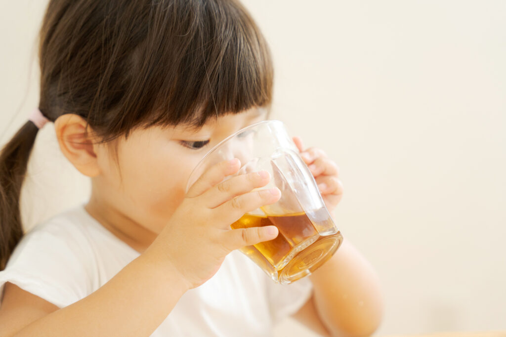 コップで飲み物を飲む女の子
