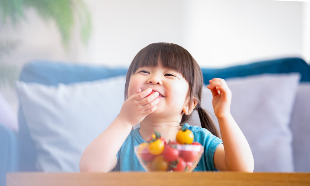 ミニトマトを笑顔で食べる女の子