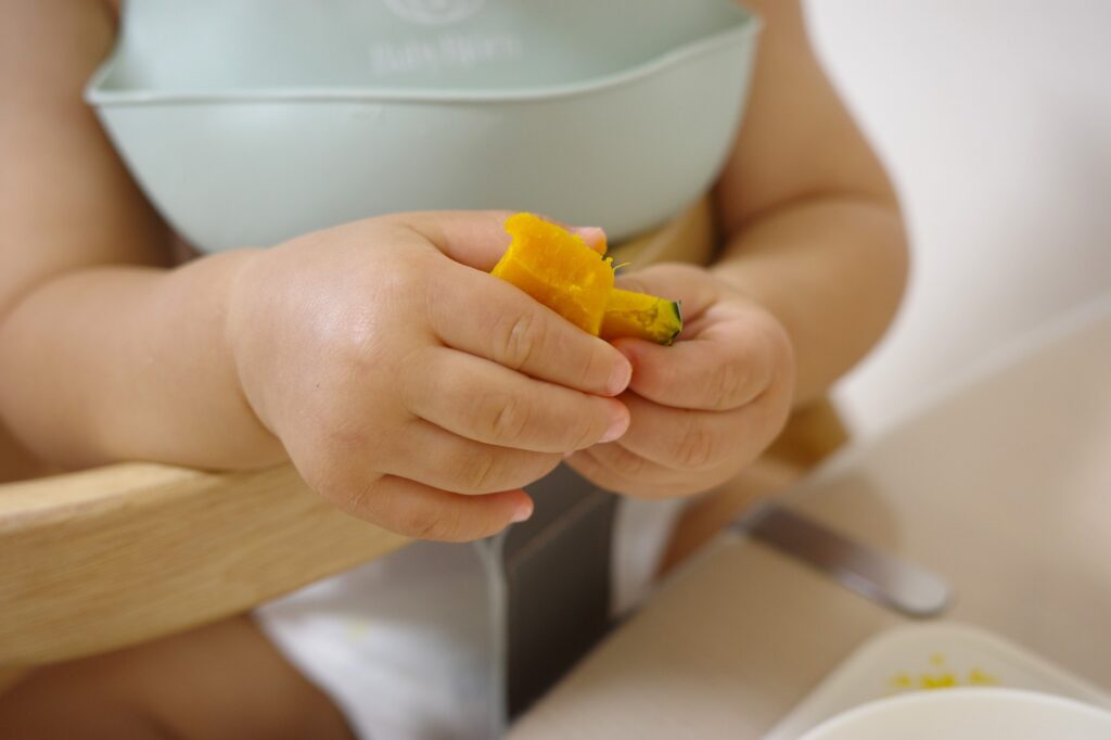 手づかみ食べでかぼちゃを握る幼児の手元