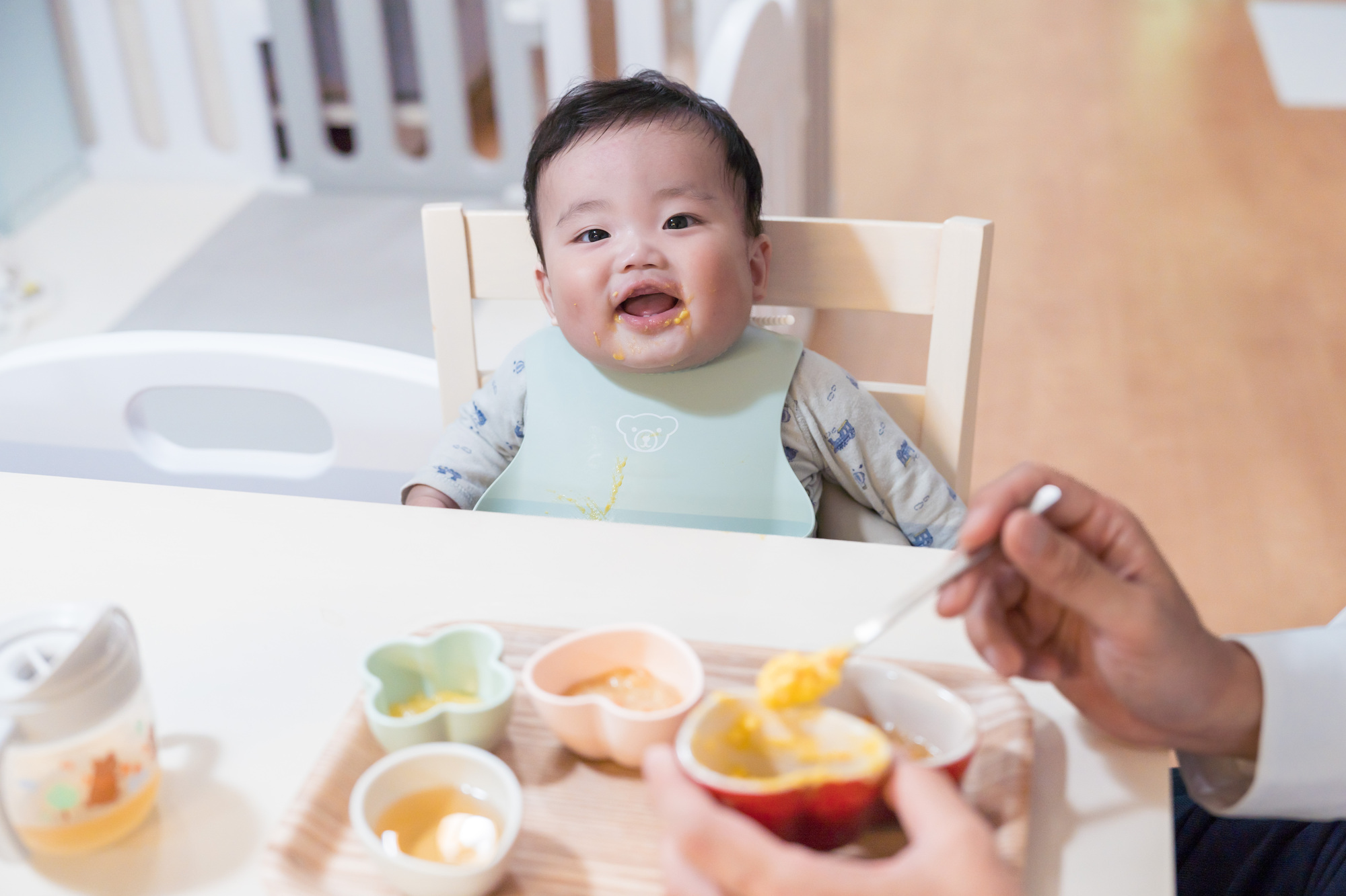 離乳食中期（7〜8ヶ月・モグモグ期）にスプーンで食べさせてもらいご機嫌な赤ちゃん
