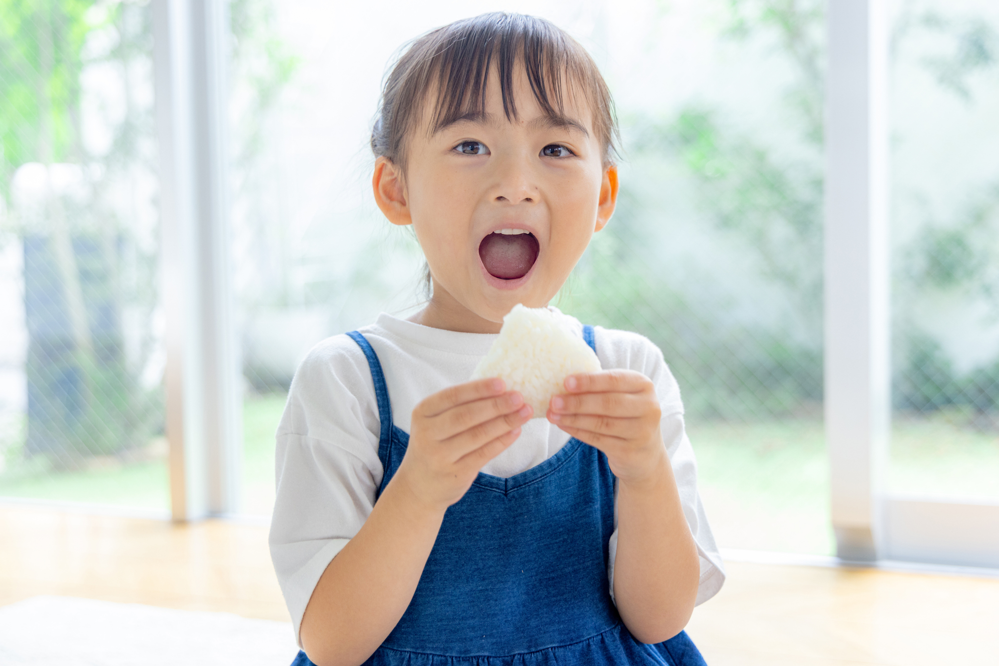 おにぎりを食べる女の子。食べムラの日でも受け入れやすい定番メニュー