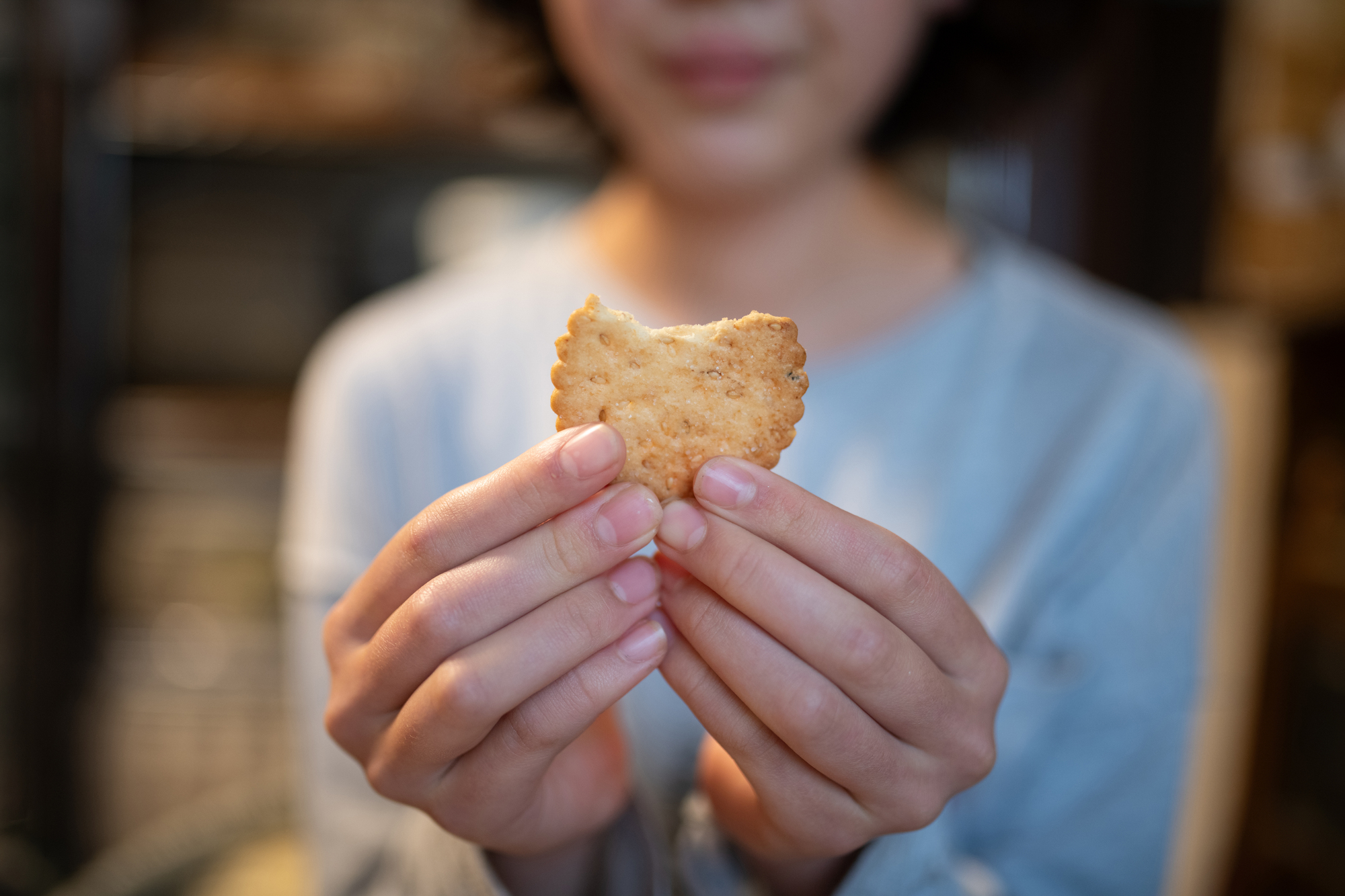 ビスケットを持つ女の子の手元。間食の時間と量を決めると食べムラが軽くなる