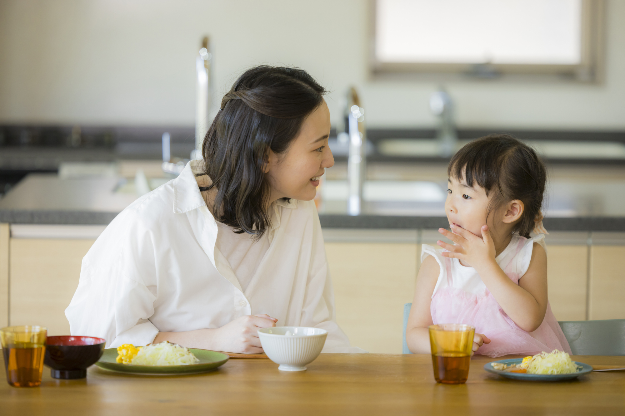 食卓を楽しそうに囲む家族。大人がおいしそうに食べると子どもも食べやすい